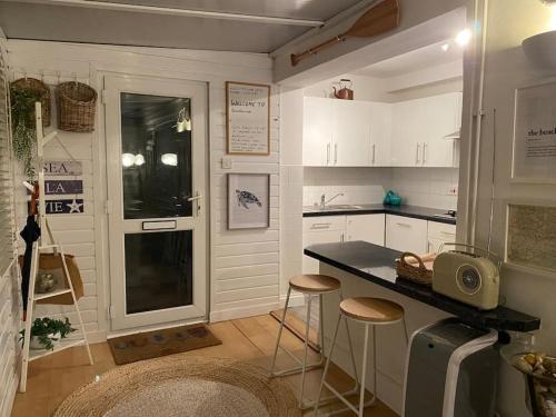 a kitchen with a counter and stools in it at Shoreline hideaway - next to the beach in Holland-on-Sea