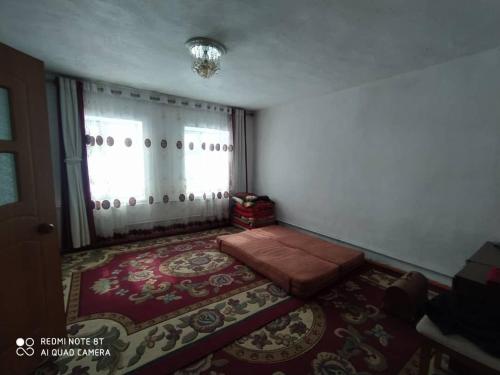 una camera con un letto, una finestra e un tappeto di Dastan Guest House a Naryn