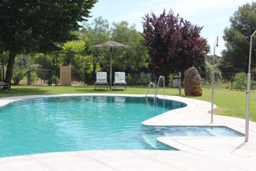 a swimming pool with two chairs and an umbrella at Hotel Rural Los Nogales in Pozo Alcón