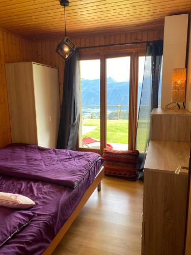 um quarto com uma cama roxa e uma grande janela em Chalet Le Petit Foyer em Salvan