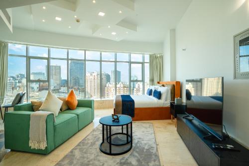 a hotel room with a green couch and a bed at CitiHome - Prime Stylish Studio in Sports City in Dubai