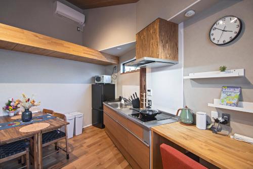 a kitchen with a table and a clock on the wall at - 旅time 沐の花 - Kinohana 新築戸建 粉浜駅 in Osaka