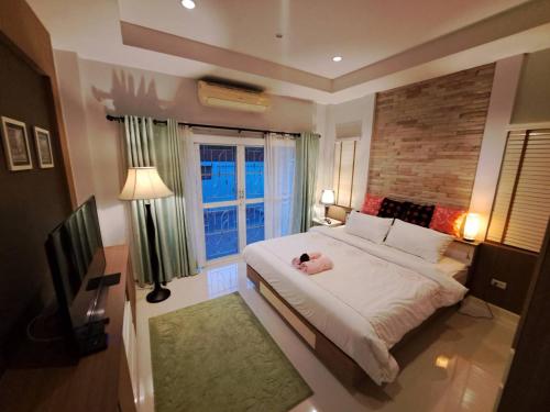 a bedroom with a large bed and a window at Jacuzzi Pool Villa in Ban Huai Yai