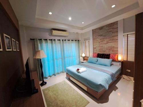 a bedroom with a large bed with blue pillows at Jacuzzi Pool Villa in Ban Huai Yai