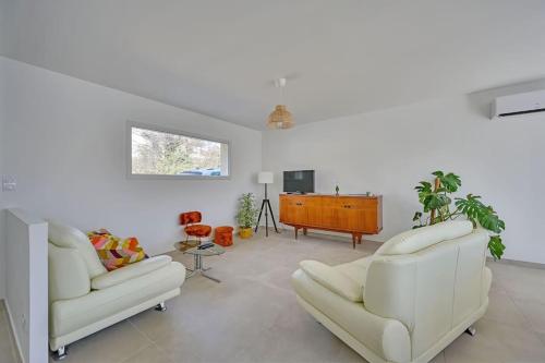 een woonkamer met 2 witte stoelen en een tv bij Villa Santa - Piscine - Wi-Fi - Proche Ventoux - idéal Cyclistes in Mormoiron