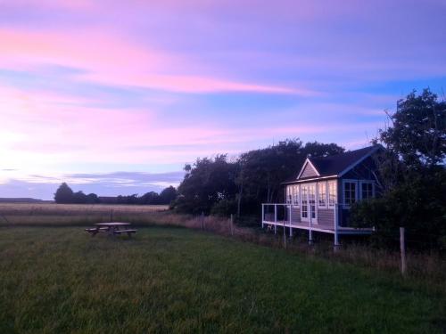 uma casa no meio de um campo com uma mesa de piquenique em Little, nice cottage for 2 with beautiful view em Lokken