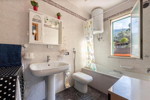 bagno con lavandino, servizi igienici e finestra di Casa Angelo a Cefalù