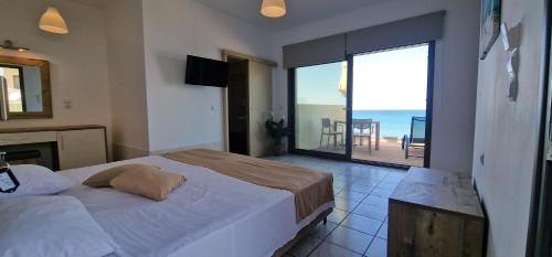 a bedroom with a bed and a view of the ocean at Almare Beach Hotel in Kokkini Khanion