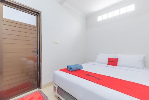 1 dormitorio con 1 cama y puerta corredera de cristal en Reddoorz near Kiara Artha Park, en Bandung