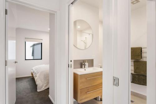 a bathroom with a sink and a mirror and a bed at Style Location New Sunny 2Bdrms Free Park in Christchurch