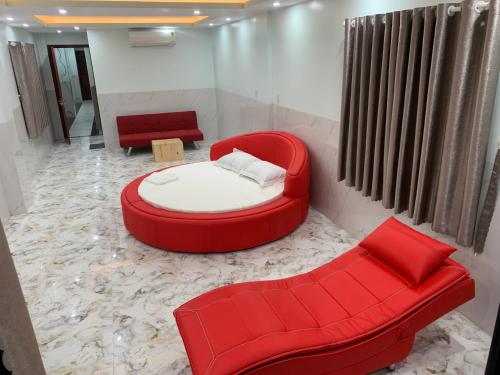 Habitación con 1 cama roja y 2 sillas rojas. en Bờ Hồ Hotel en Ấp Ðông An (1)