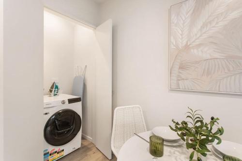 a white room with a washing machine and a table at Style Location New Sunny 2Bdrms Free Park in Christchurch