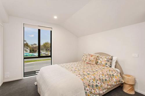 a bedroom with a bed and a large window at Style Location New Sunny 2Bdrms Free Park in Christchurch