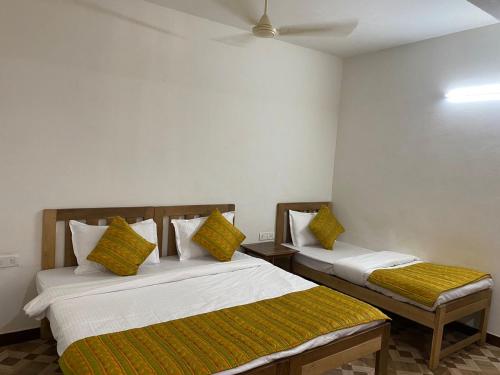 a bedroom with two beds with yellow pillows at Calangute Beach Prime in Calangute
