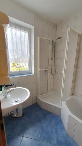 a white bathroom with a sink and a shower at Gästezimmer Carmen in Schwendi