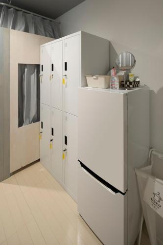 a kitchen with white cabinets and a white refrigerator at Iwatoyama Hostel in Kyoto