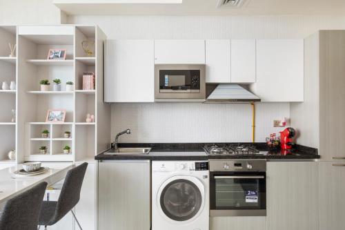 a kitchen with a washing machine and a microwave at Modern Studio in Arjan-Dubailand in Dubai