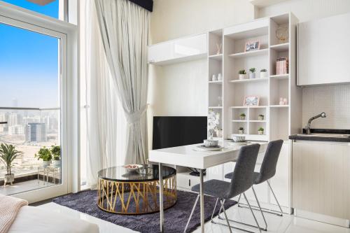 eine Küche und ein Wohnzimmer mit einem Tisch und Stühlen in der Unterkunft Modern Studio in Arjan-Dubailand in Dubai