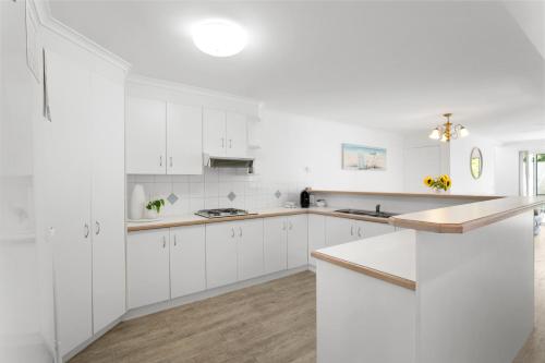 a white kitchen with white cabinets and a counter top at Noosa Sunseeker-walk to cafes & river, pet friendly in Noosaville