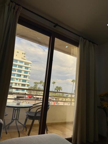 Schlafzimmer mit Blick auf einen Balkon mit einem Tisch in der Unterkunft Ithaki Phinikoudes Apartment No. 105 in Larnaka