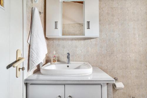 uma casa de banho com um lavatório branco e um espelho. em Angela Apartment em Dhalamanára