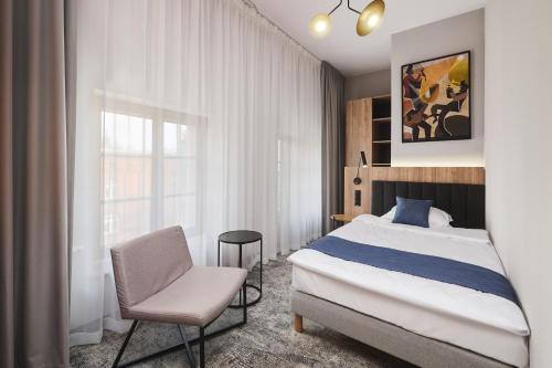 um quarto com uma cama, uma cadeira e uma janela em Halo Szczecin em Szczecin