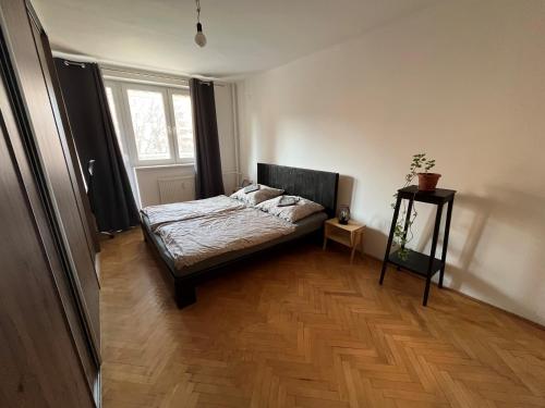 Schlafzimmer mit einem Bett und Holzboden in der Unterkunft Útulný byt blízko centra in Koliba