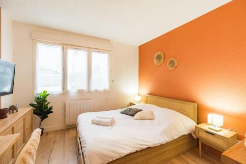 a bedroom with a large bed with an orange wall at Studio l'escale Bretonne - Saint-Brieuc in Saint-Brieuc