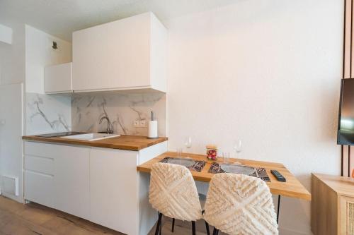 una cocina con armarios blancos y una mesa con 2 sillas en Studio l'escale Bretonne - Saint-Brieuc en Saint-Brieuc