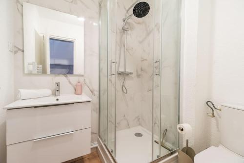 a white bathroom with a shower and a sink at Studio l'escale Bretonne - Saint-Brieuc in Saint-Brieuc