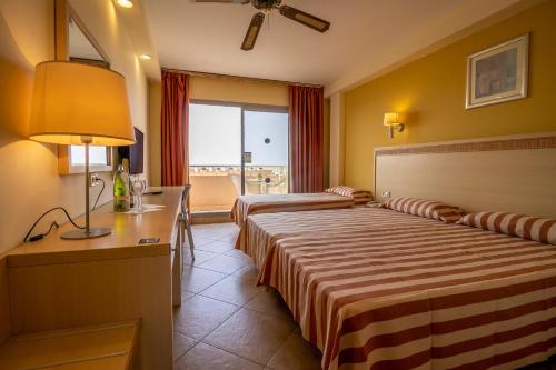 a hotel room with two beds and a desk at ALEGRIA Fenix Family in Roquetas de Mar