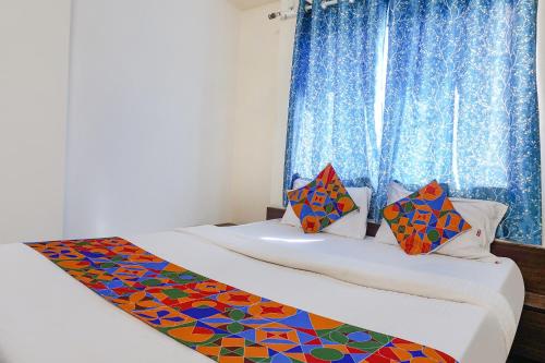 two beds in a room with blue curtains at FabHotel Gokul Lodge in Pune