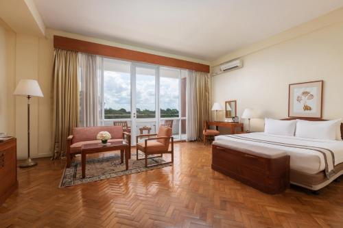 ヤンゴンにあるインヤ レイク ホテルのベッド、デスク、椅子が備わるホテルルームです。