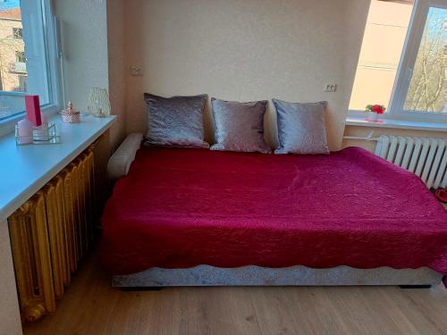 ein Schlafzimmer mit einem großen Bett mit einer roten Decke in der Unterkunft Parko apartamentai Self check in in Klaipėda