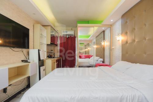 um quarto com uma grande cama branca e uma televisão em RedLiving Apartement Cinere Resort By YK rooms Tower Kintamani em Gandul