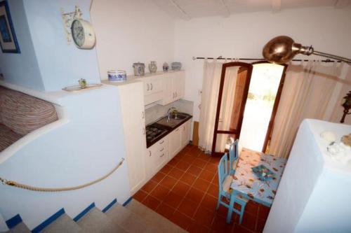 a kitchen with white cabinets and a table and a chair at Villa Redinoce in Marciana