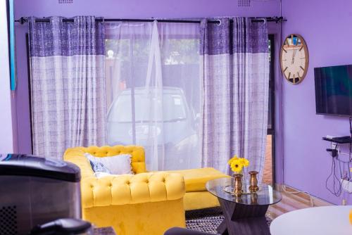 a living room with a yellow couch and a clock at The Crescent Byo in Bulawayo