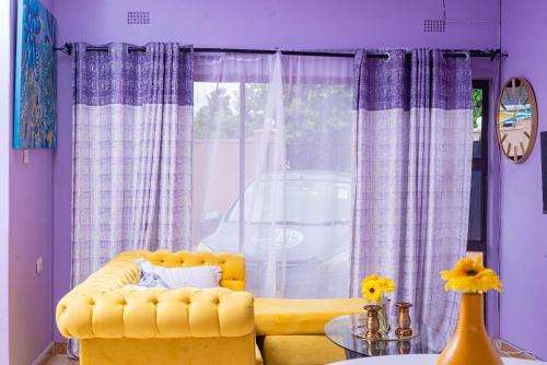 a living room with a yellow couch and a window at The Crescent Byo in Bulawayo