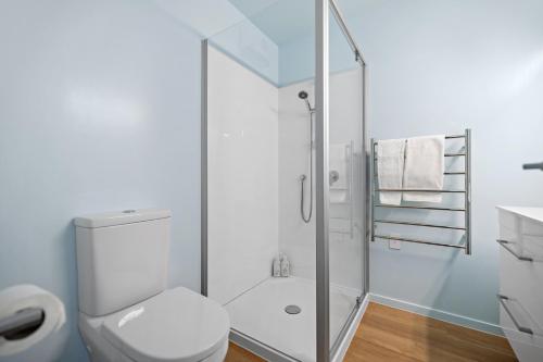 een witte badkamer met een douche en een toilet bij Luxury Lakeside Retreat in Queenstown