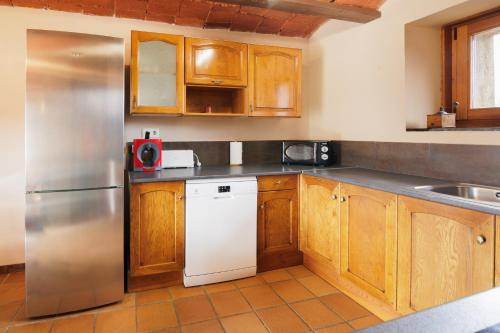 a kitchen with wooden cabinets and a stainless steel refrigerator at Masia d'en cot in Puigcerdà