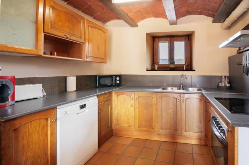 a kitchen with wooden cabinets and a white dishwasher at Masia d'en cot in Puigcerdà