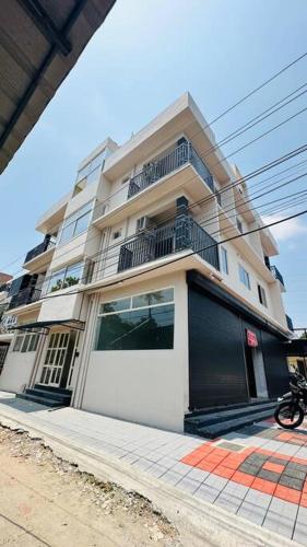 a tall white building with a balcony on a street at Peaceful Living Solo Suites in Ernakulam