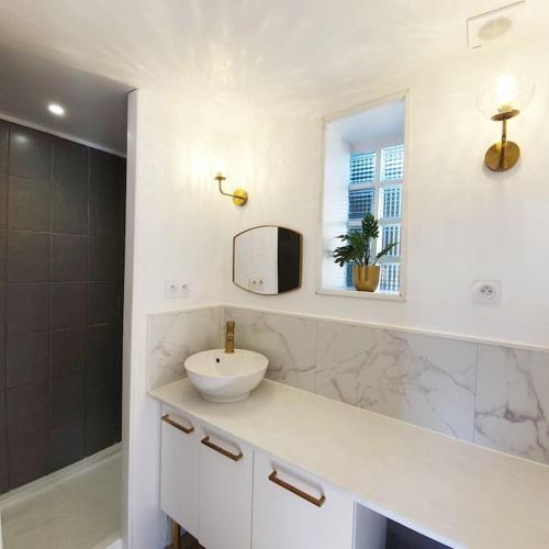 une salle de bain blanche avec un lavabo et un miroir dans l'établissement Le clos Langella, à Léognan