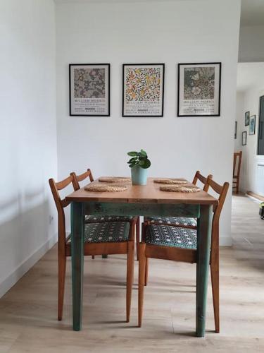 une table en bois avec des chaises et une plante en pot au-dessus dans l'établissement Le clos Langella, à Léognan