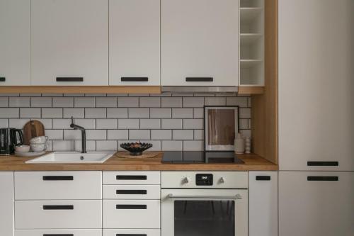 a kitchen with white cabinets and a sink at HARBOR APARTMENTS - Damrota in Katowice