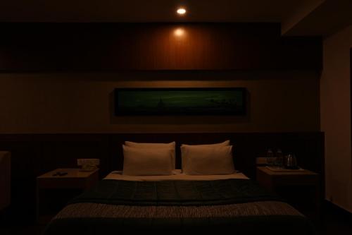 a bedroom with a bed with white pillows and two tables at Vgp Golden Beach Resort in Chennai
