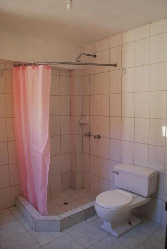 a bathroom with a pink shower curtain and a toilet at Hospedaje Kamila in Cusco