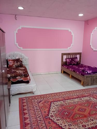 a room with two beds and a pink wall at استراحة وزنه in Buraydah