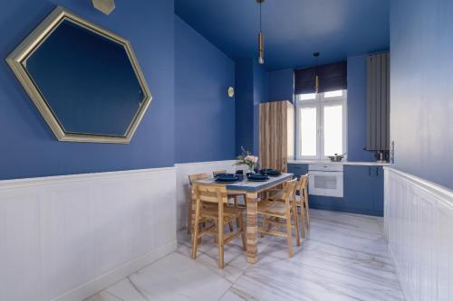 kuchnia z niebieskimi ścianami, stołem i krzesłami w obiekcie Apartment in Cracow Center with Air Conditioning, Desk and Balcony by Renters w Krakowie