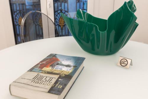 a book and a green vase on a table at San Nicolò Suites in Trieste